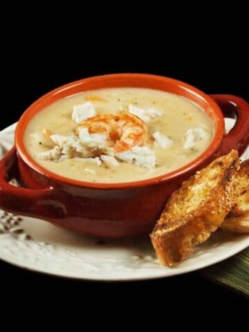 brown crock of shrimp and crab chowder with toasts on a white plate