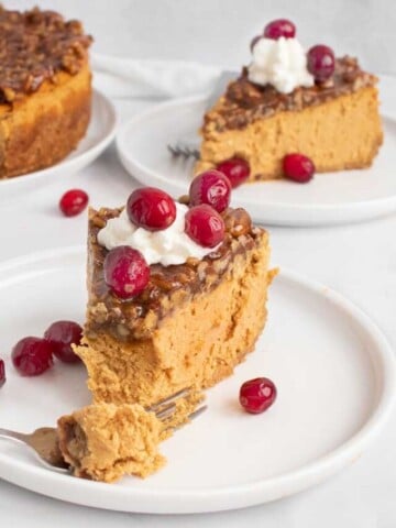 slices of pumpkin. praline cheesecake on white plates with the rest of the cheesecake in the background