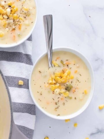 pot of corn chowder next to two bowls of corn chowder