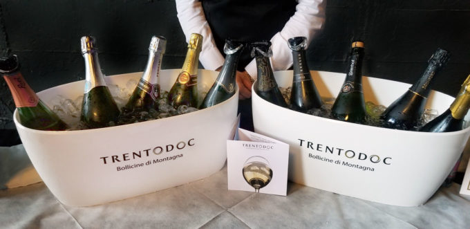 bottles of TrentoDOC sparkling wine in white tubs on a table