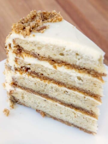 slice of four layer banana crunch cake on a white plate