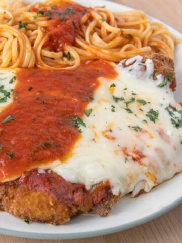 chicken parm on a white plate with pasta