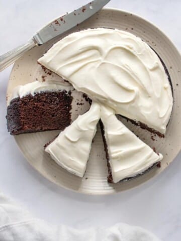 overhead shot of Guinness chocolate cake sliced on a white platter with a slice on a small plate