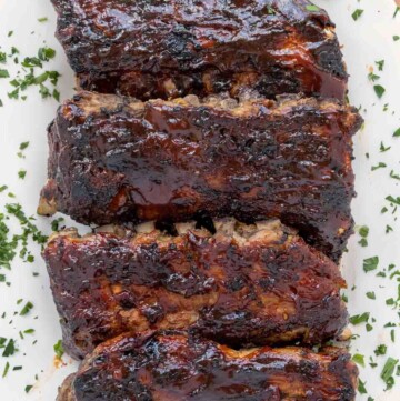 overhead view of barbecued half racks of baby back ribs on a white platter