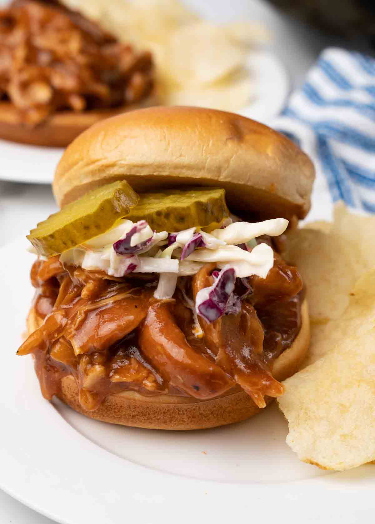 bbq chicken sandwich with cole slaw and pickles on bun.