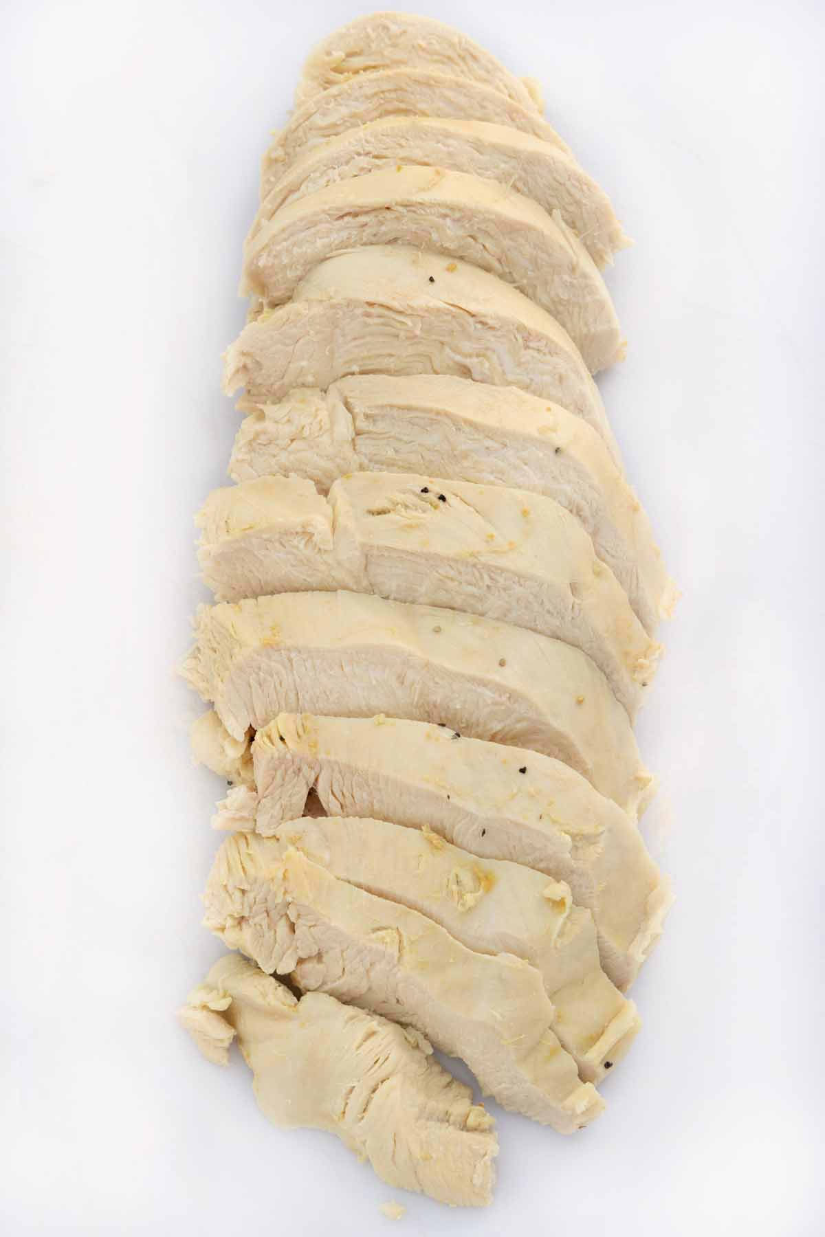 sliced poached chicken breast on white cutting board