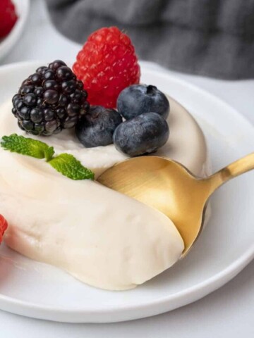 taking a spoonful out of the panna cotta with berries.