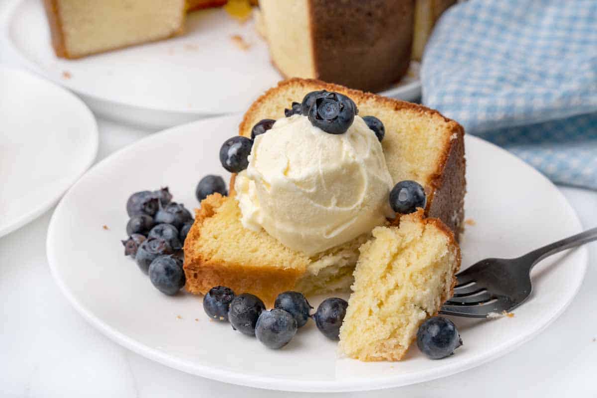 slice of sour cream pound cake with vanilla ice cream and blueberries on white plate.