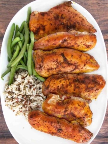 Smoked chicken breasts on a white platter.