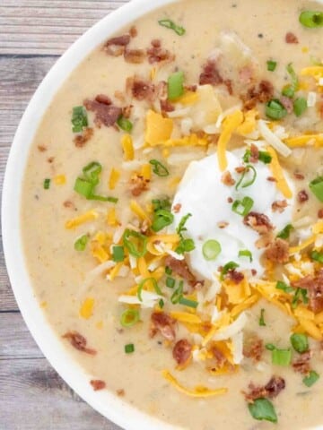 Slow cooker loaded potato soup in a white bowl.