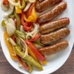 Smoked sausage, peppers, and onions on a white platter.