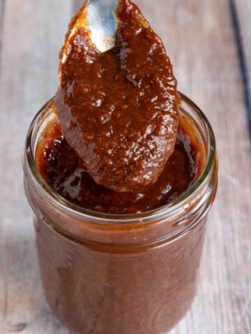 Chamoy sauce in a jar with a spoon coming out of the jar.