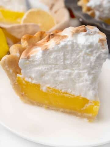 Slice of lemon meringue pie on a white plate.