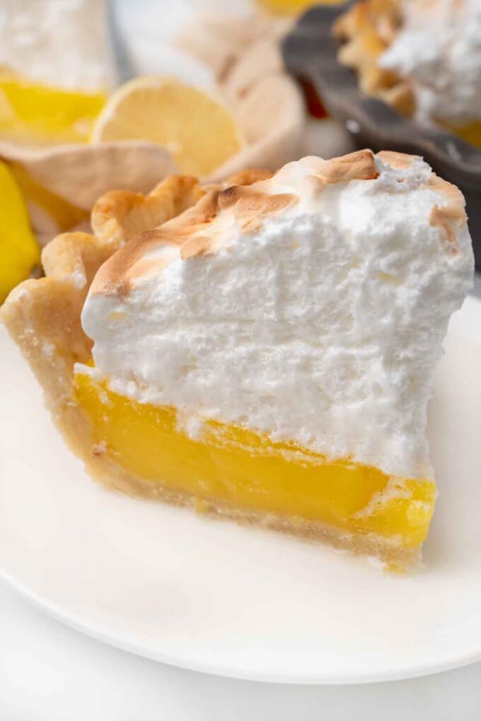 Slice of lemon meringue pie on a white plate.