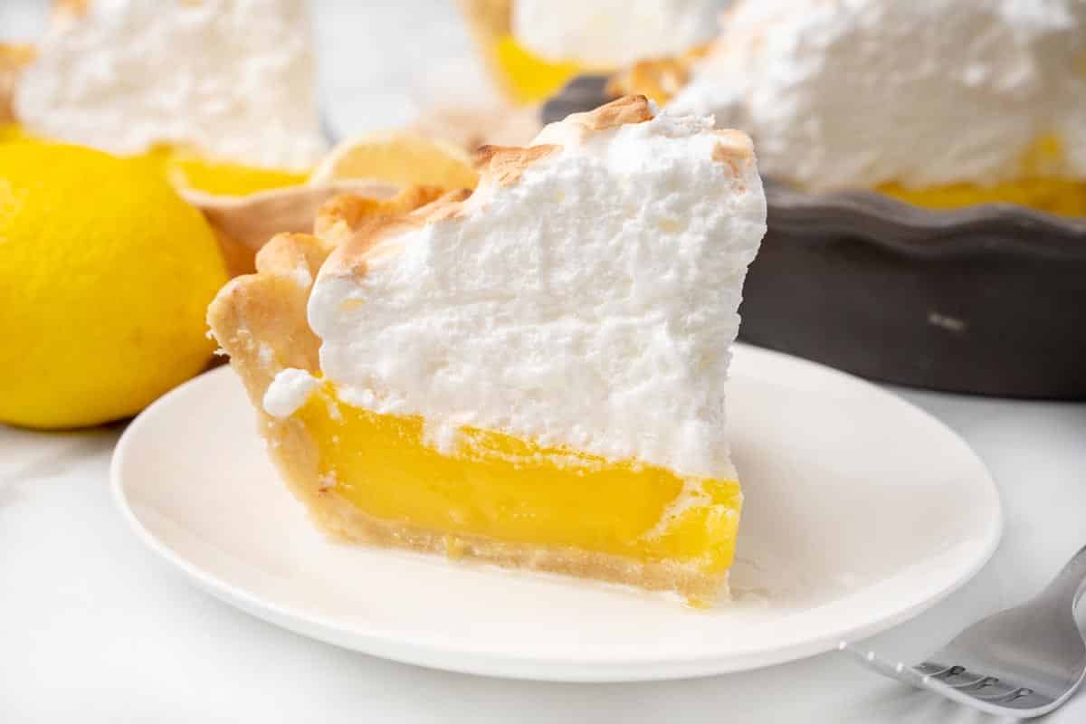 Slice of lemon meringue pie on a white plate.