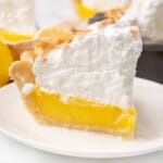 Slice of lemon meringue pie on a white plate.