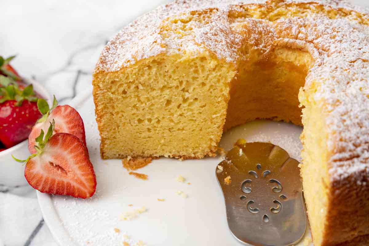 view of section of chiffon cake on a white platter with strawberries.