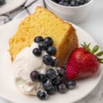 Slice of chiffon cake with whipped cream and berries on a white plate.