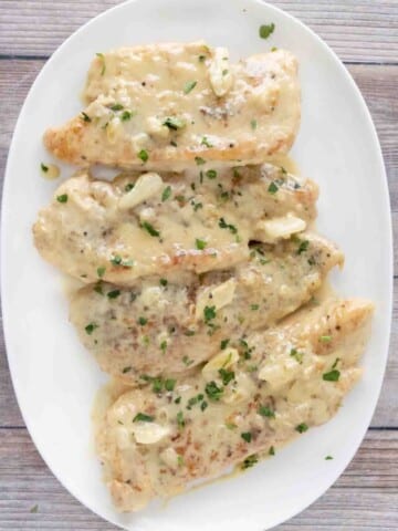 Creamy garlic chicken on a white platter.