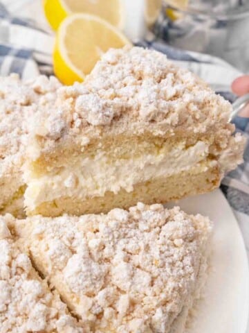 Slice of lemon cream cake being taken out of hte whole cake.