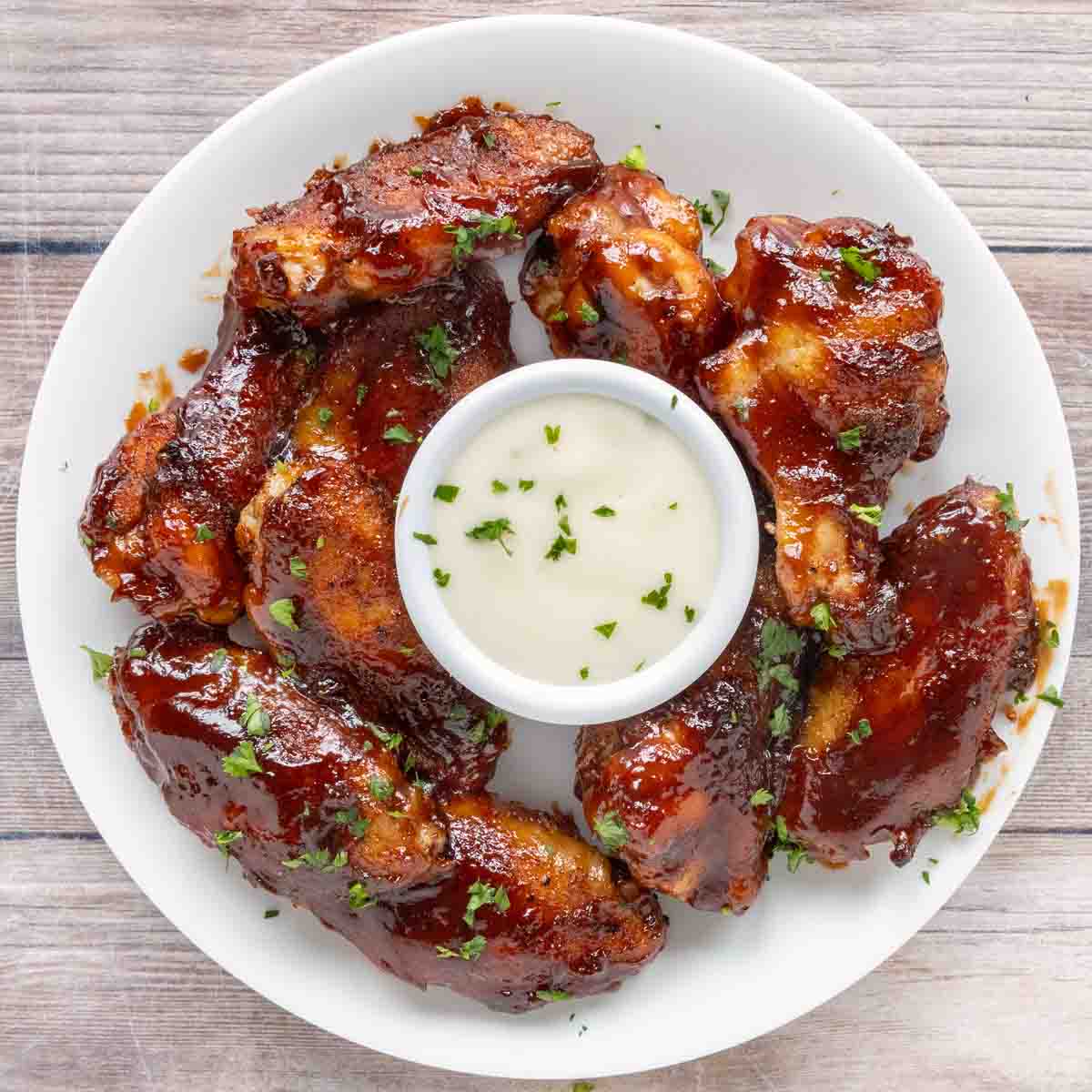 honey barbecue chicken wings with dipping sauce on a white plate.