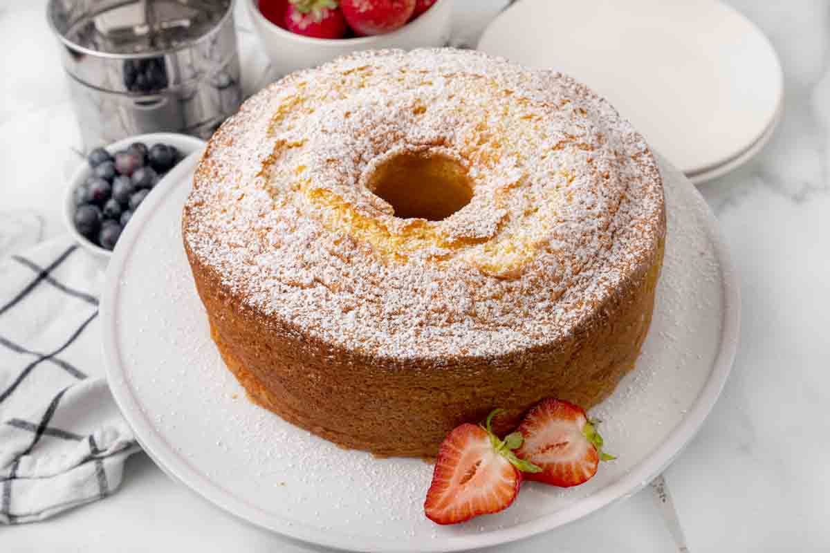 Whole chiffon cake on a cake pedestal with 2 strawberry halves.