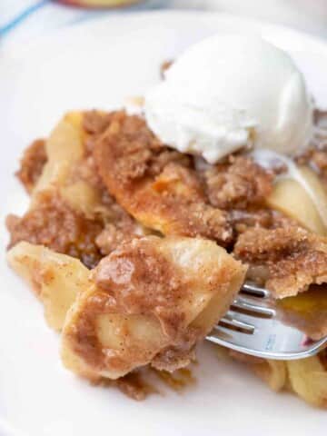 Apple Brown Betty with ice cream on a white plate.