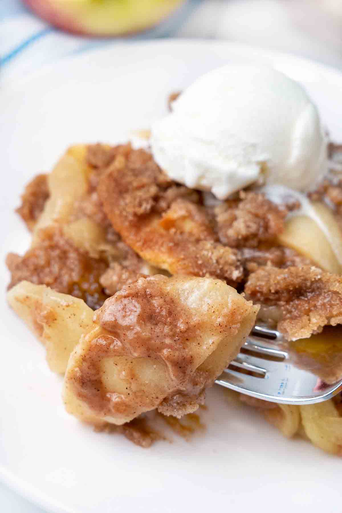 Apple Brown Betty with ice cream on a white plate.