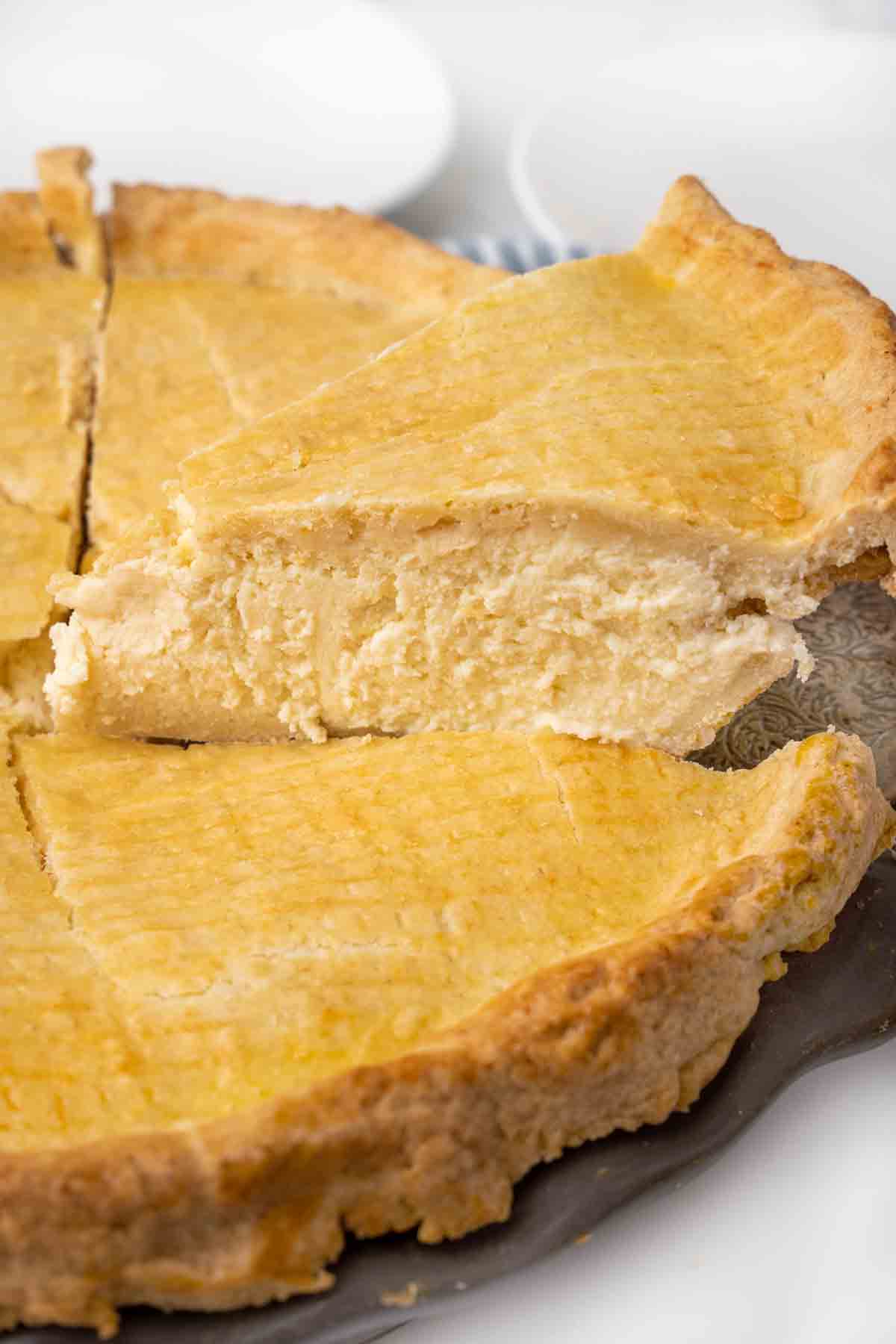 Slice of ricotta pie being taken out of the whole pie.