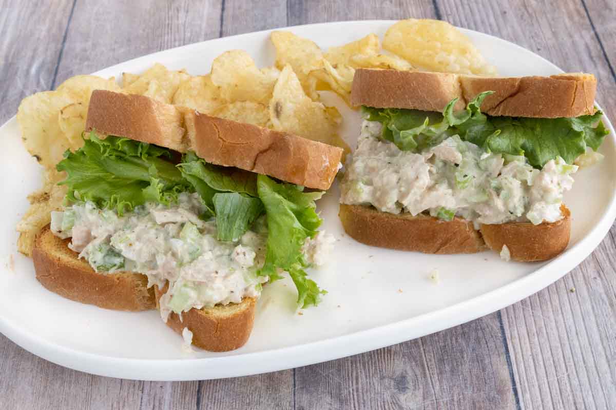 two tuna salad sandwiches on a white platter.