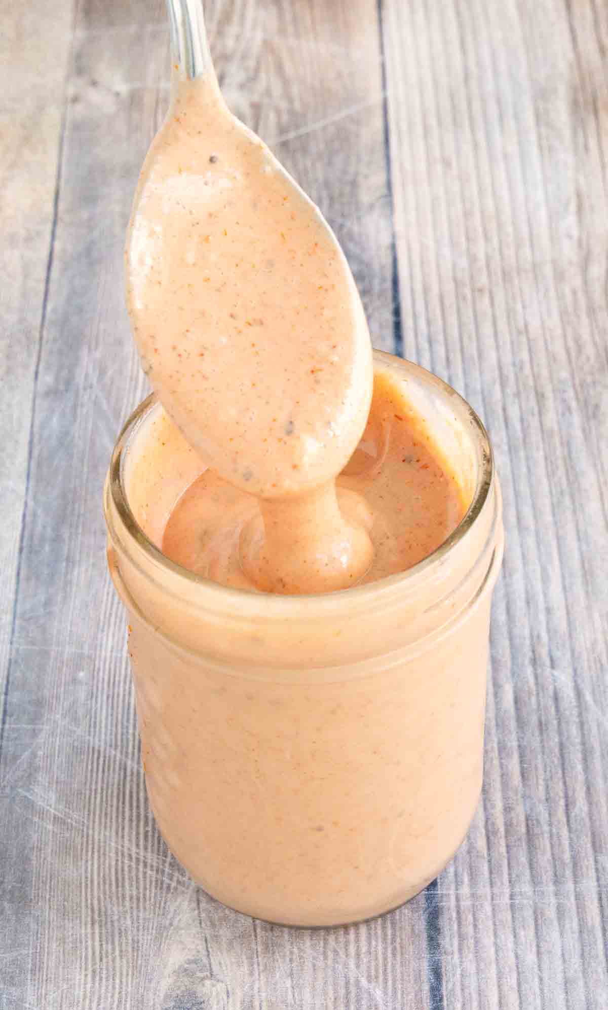 Burger sauce in a glass jar with a spoon coming out.