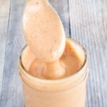 Pink sauce in a glass jar with a spoon coming out.