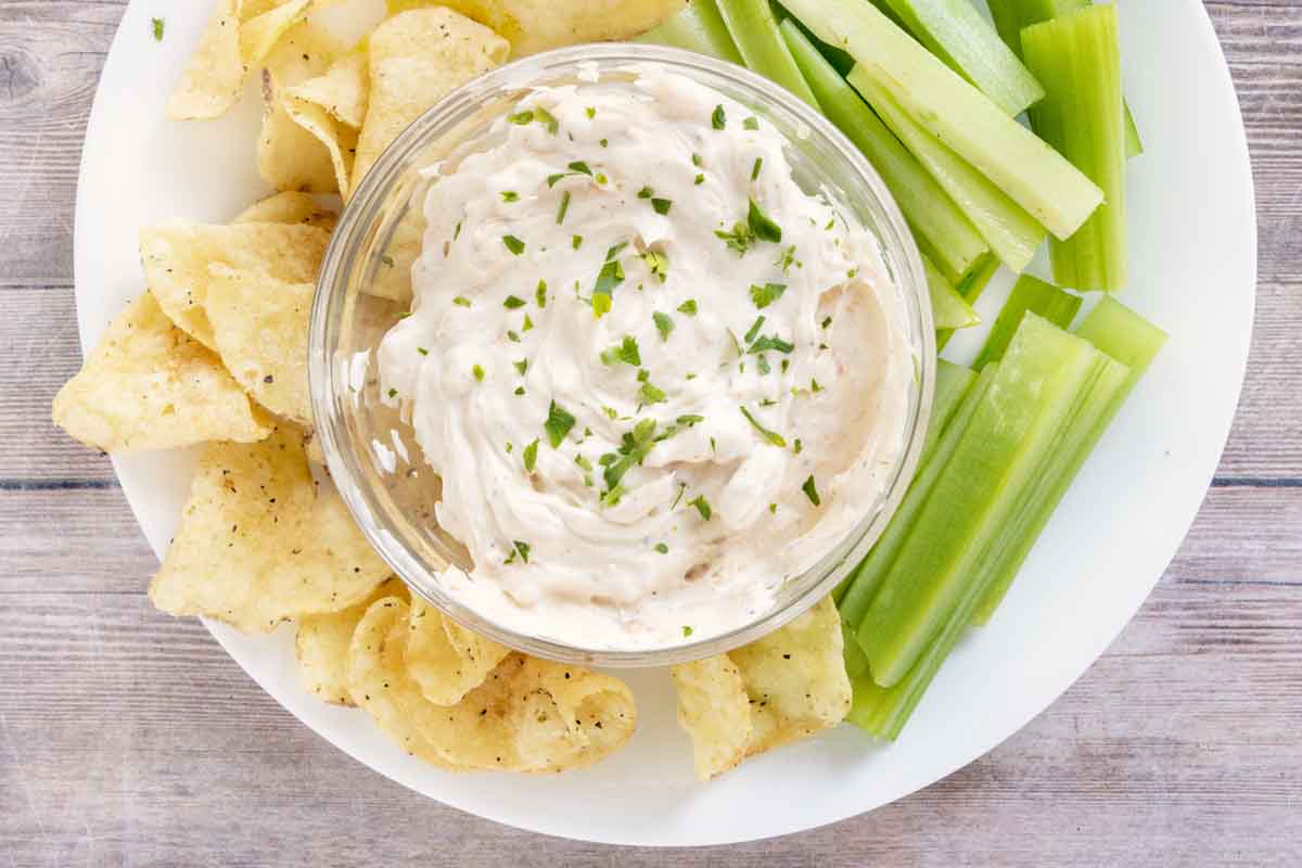 Whipped smoked cream cheese on a white plate with. chips and celery.