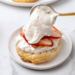 Adding homemade whipped cream to strawberry shortcake.