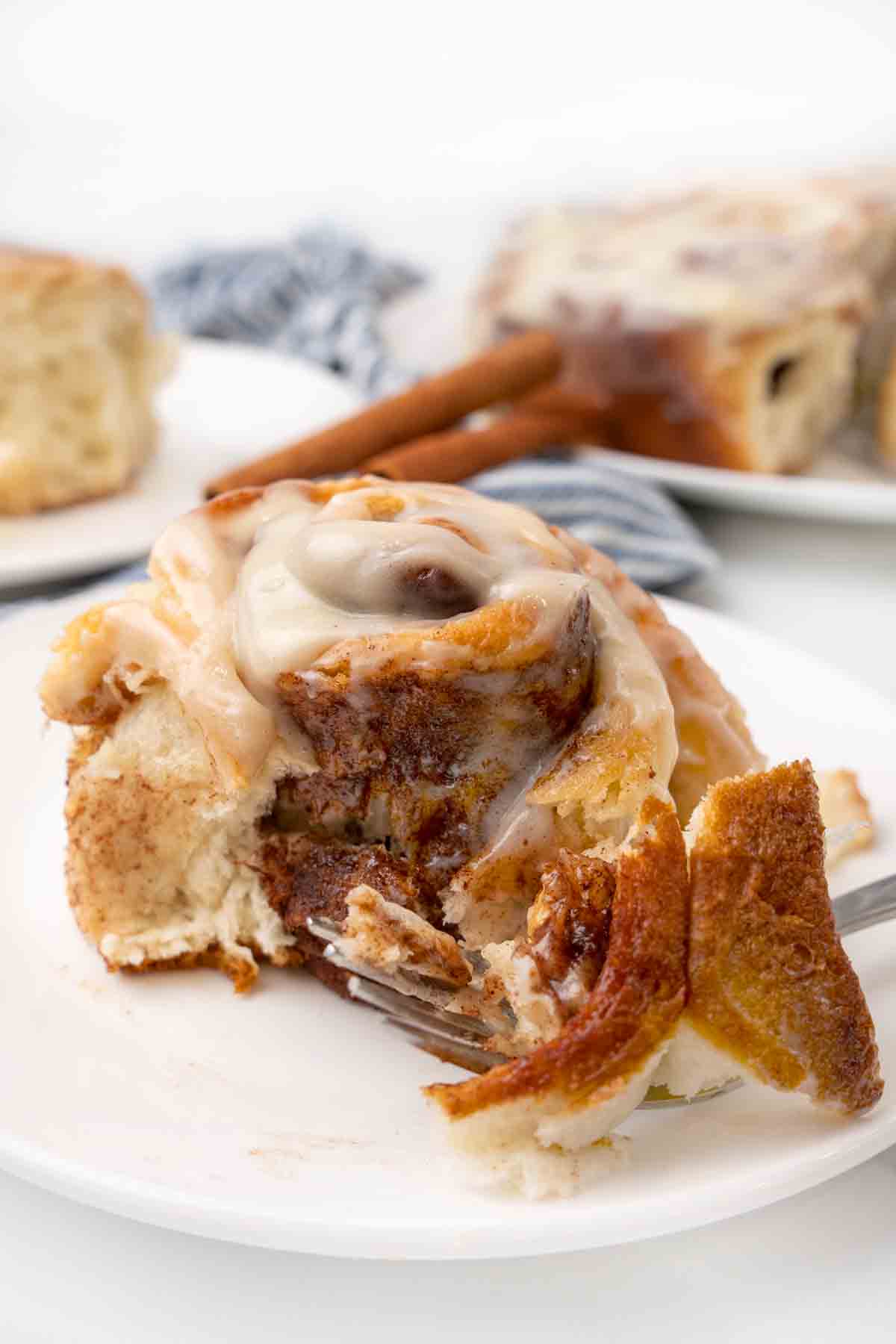 easy cinnamon roll on a white plate with a fork taking a piece out of the roll