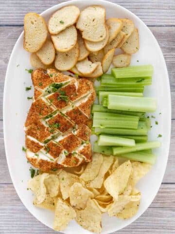 Smoked cream cheese with chips, toasts and celery on a white platter.