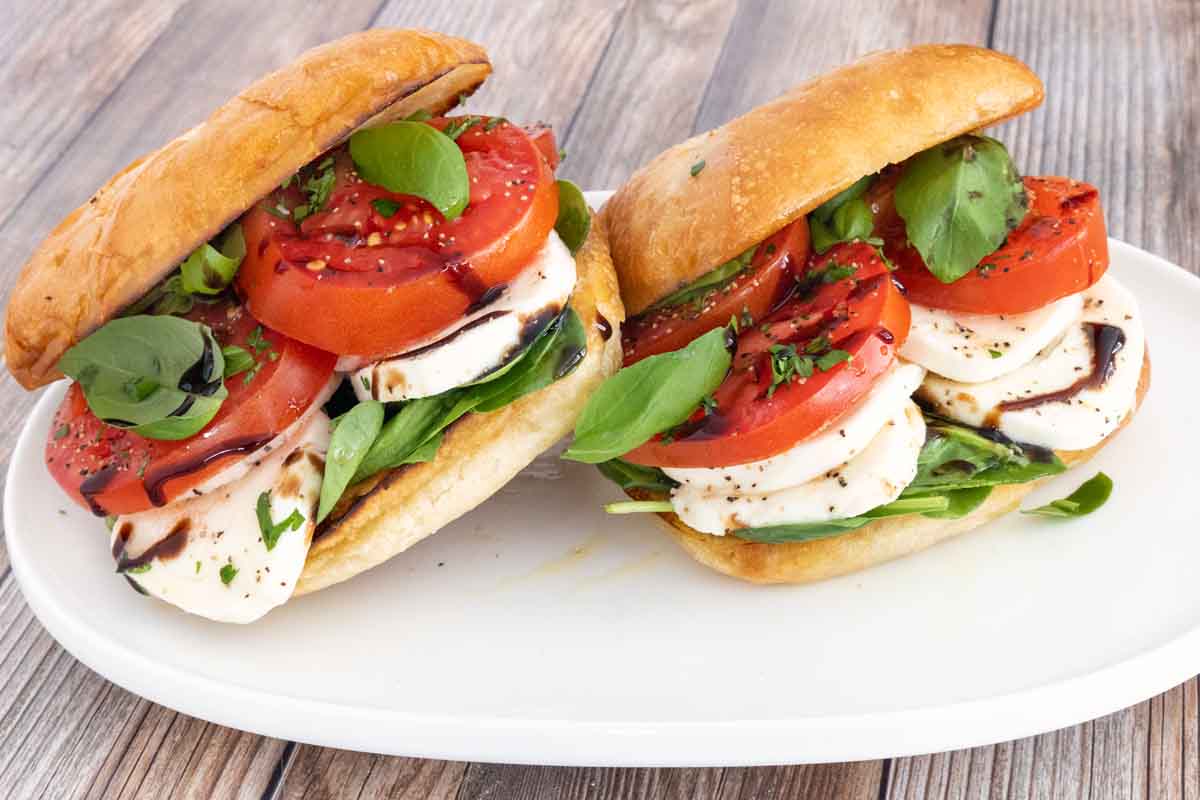 Two Caprese sandwiches on a white platter.