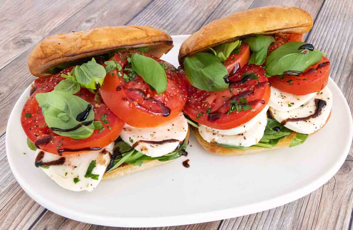 Two Caprese sandwiches on a white platter.