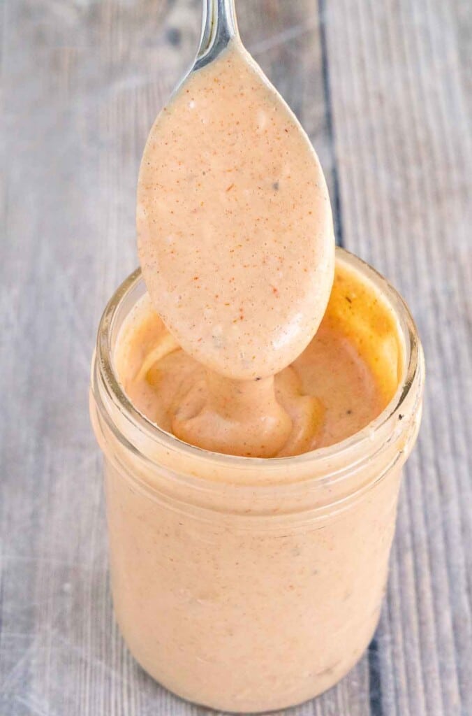 Comeback sauce in a glass jar with a spoon coming out.