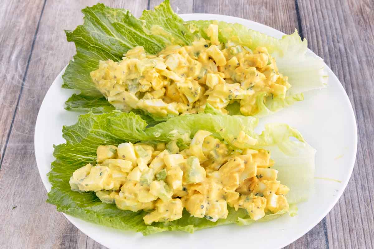 Egg Salad on romaine leaves on a white plate.