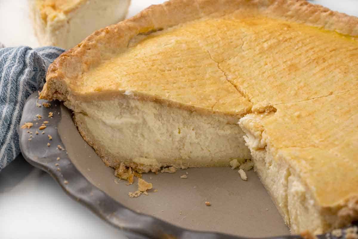 Whole ricotta pie in the pie plate with slices removed.