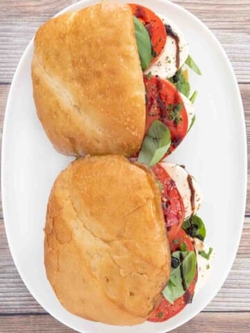 Two Caprese sandwiches on a white platter.