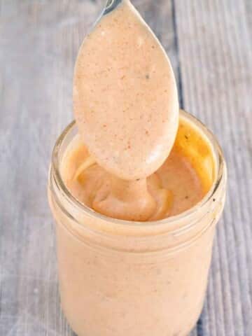 Comeback sauce in a glass jar with a spoon coming out.