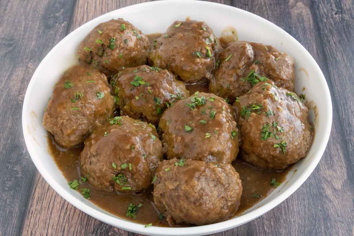 Smoked meatballs and gravy in a white bowl.