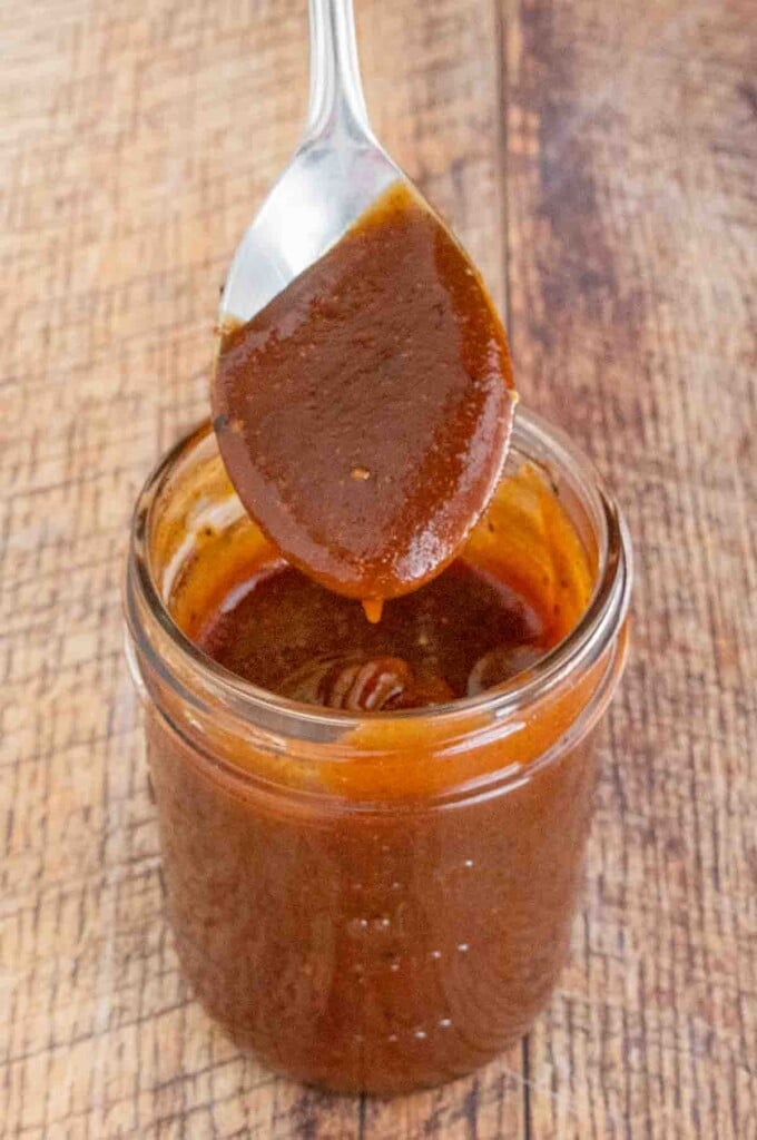 Memphis Barbecue Sauce in a glass jar with a spoon coming out.