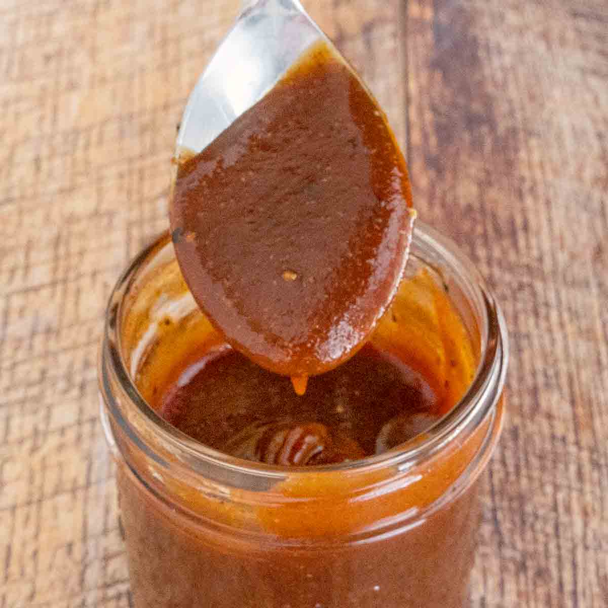 Memphis Barbecue Sauce in a glass jar with a spoon coming out.