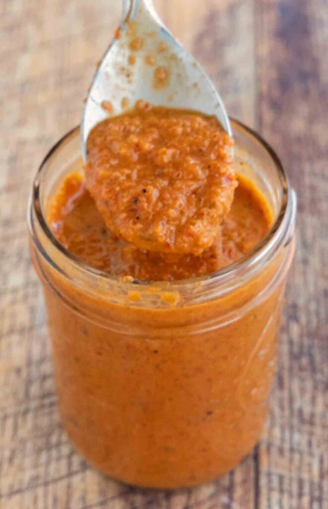 Peri-Peri Sauce in a glass jar with a spoon coming out of the jar.