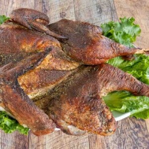 Roasted Spatchcock Turkey on a platter lined with romaine leaves.