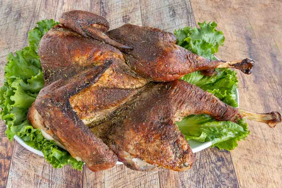 Roasted Spatchcock Turkey on a platter lined with romaine leaves.