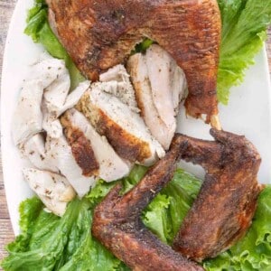 Cut up Spatchcock Turkey on a platter lined with romaine leaves.